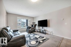Living area featuring a large window, neutral wall tones, textured ceiling, and mixed flooring with carpet and tile - 