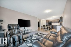 Open-concept living space featuring neutral wall tones, recessed lighting, and a kitchen with dark cabinetry, white subway tile backsplash, and a breakfast bar - 