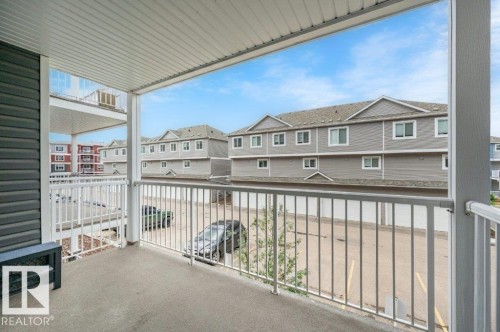 Covered patio space featuring a concrete floor and white railing - 219 1820 Rutherford Road, Edmonton, AB 