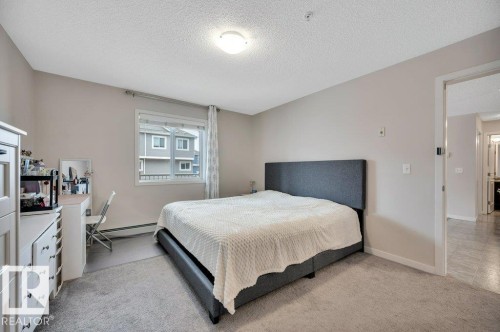 Carpeted bedroom with neutral wall tones and a single window - 219 1820 Rutherford Road, Edmonton, AB 