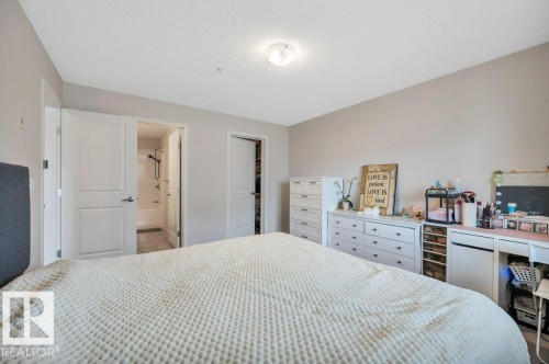 Bedroom featuring neutral-toned walls, white trim, and a textured ceiling - 219 1820 Rutherford Road, Edmonton, AB 