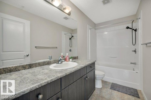 Bathroom featuring a single vanity with a laminate countertop, undermount sink, and dark wood-finish cabinetry - 219 1820 Rutherford Road, Edmonton, AB 