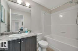 Full bathroom featuring a single vanity with wood-finish cabinetry, a white oval sink, and a speckled countertop - 