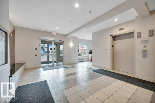 Building foyer featuring tile flooring, recessed lighting, double glass entry doors, and a passenger elevator - 219 1820 Rutherford Road, Edmonton, AB 