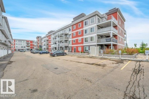 Contemporary multi-story building featuring a red and grey facade with multiple private balconies - 219 1820 Rutherford Road, Edmonton, AB 