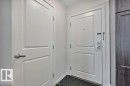 Entryway featuring a panel door with brushed nickel hardware, a secure entry door with a deadbolt and chain lock, and dark wood-finish cabinetry - 219 1820 Rutherford Road, Edmonton, AB 