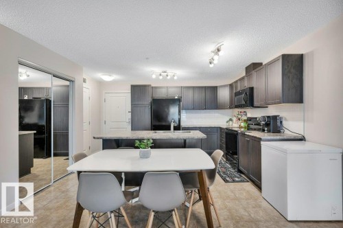 Open-concept kitchen and dining area with wood-finish flooring - 219 1820 Rutherford Road, Edmonton, AB 