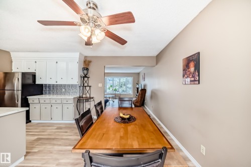 Kitchen and dining area featuring wood-finish flooring, white cabinetry, a patterned backsplash, and an open concept layout - 9813 152 Street, Edmonton, AB 