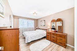 Bedroom featuring wood-finish flooring, a ceiling-mounted light fixture, and a window with sheer curtains - 