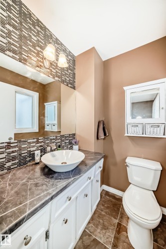 Bathroom with a vessel sink, white vanity cabinetry, and a dark stone-look countertop - 9813 152 Street, Edmonton, AB 