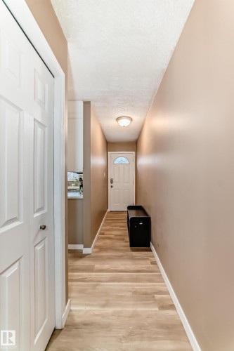 Entryway featuring wood-finish flooring, neutral wall tones, a white paneled door, and a flush-mount ceiling light - 9813 152 Street, Edmonton, AB 