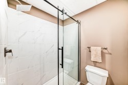 Full shower enclosure with white tile surround, matte black fixtures, and a glass sliding door - 