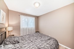 Bedroom featuring light-colored walls, a window with sheer curtains, wood-finish flooring, and a ceiling-mounted light fixture - 
