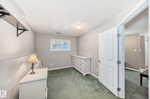 Room featuring neutral wall tones, green carpeting, and a white interior door - 9813 152 Street, Edmonton, AB 