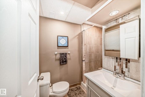 Full bathroom featuring a white vanity with integrated sink, chrome faucet, and mosaic tile backsplash - 9813 152 Street, Edmonton, AB 