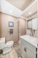 Bathroom with wood-finish flooring, a white toilet, and a vanity with a white countertop - 