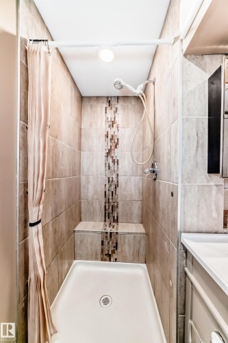 Tiled shower stall featuring a mosaic accent strip, built-in bench, and a white shower pan - 9813 152 Street, Edmonton, AB 