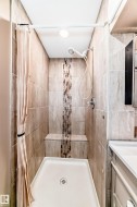Tiled shower stall featuring a mosaic accent strip, built-in bench, and a white shower pan - 