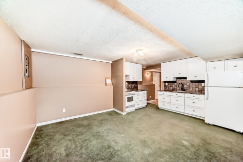 Kitchenette featuring white cabinetry, a full-size refrigerator, an electric range, and a sink with a black faucet - 9813 152 Street, Edmonton, AB 
