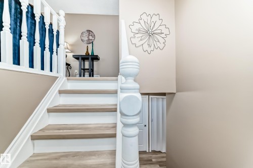 Staircase featuring wood-finish treads, white risers, and a white baluster railing - 9813 152 Street, Edmonton, AB 
