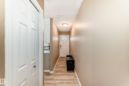 Entryway featuring light wood-finish flooring, neutral-toned walls, and a white front door with a decorative arch window - 9813 152 Street, Edmonton, AB 
