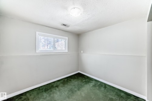 Interior room featuring green carpeting, neutral wall finishes, white baseboards, and a white-framed window - 9813 152 Street, Edmonton, AB 