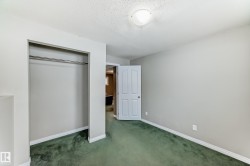 Room featuring green carpeting, light gray walls, white baseboards, and a built-in closet with a metal hanging rod - 
