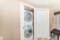 Dedicated laundry alcove featuring a stacked washer and dryer unit - 
