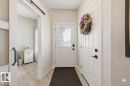 Entryway featuring a white paneled door with integrated blinds, matte black hardware, and wood-finish flooring - 27 11 Dalton Link, Spruce Grove, AB 