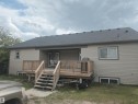 Rear exterior featuring a covered deck, wood railings, and stairs leading to the yard - 4808 50 Avenue, Lamont, AB 