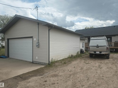 Detached garage featuring light-colored siding and a panel-style garage door - 4808 50 Avenue, Lamont, AB 