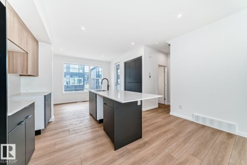 Modern kitchen with a central island featuring a white countertop and black cabinetry - #66 5 Rondeau Dr, St. Albert, AB - Indoor Photo Showing Kitchen