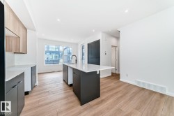 Modern kitchen with a central island featuring a white countertop and black cabinetry - 
