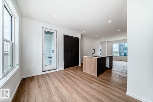 Open-concept living area featuring wood-finish flooring, recessed lighting, and a kitchen island with a quartz countertop and integrated sink - #66 5 Rondeau Dr, St. Albert, AB - Indoor