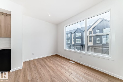 Bright interior space featuring a large picture window, light wood-finish flooring, white baseboards, and a recessed ceiling light - #66 5 Rondeau Dr, St. Albert, AB - Indoor Photo Showing Other Room