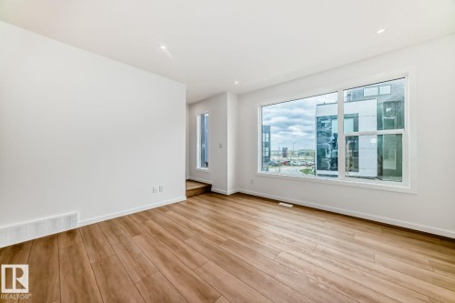 Spacious room with wood-finish flooring, white walls, and recessed lighting - #66 5 Rondeau Dr, St. Albert, AB - Indoor Photo Showing Other Room