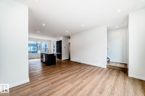 Spacious open-concept interior featuring light wood-finish flooring and recessed ceiling lighting - #66 5 Rondeau Dr, St. Albert, AB - Indoor