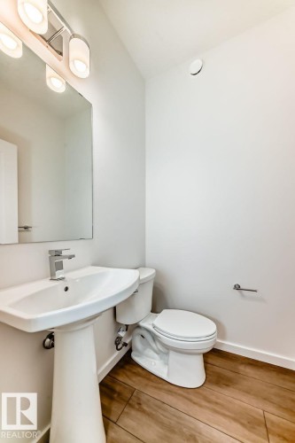 Pedestal sink with a polished chrome faucet, rectangular wall mirror, and modern three-bulb vanity light fixture - #66 5 Rondeau Dr, St. Albert, AB - Indoor Photo Showing Bathroom