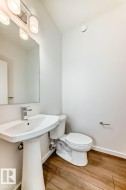 Pedestal sink with a polished chrome faucet, rectangular wall mirror, and modern three-bulb vanity light fixture - 