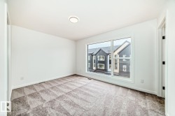 Bright room featuring a large window, neutral white walls, and geometric pattern carpeting - 