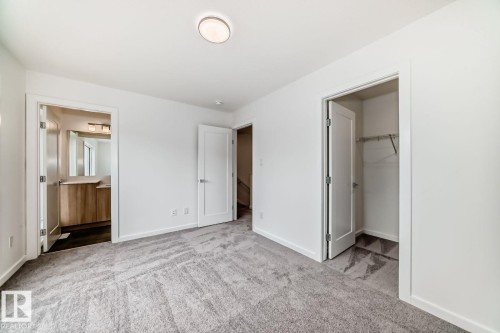 Spacious room featuring gray patterned carpeting, white walls, and a contemporary ceiling light fixture - #66 5 Rondeau Dr, St. Albert, AB - Indoor