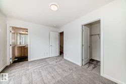 Spacious room featuring gray patterned carpeting, white walls, and a contemporary ceiling light fixture - 