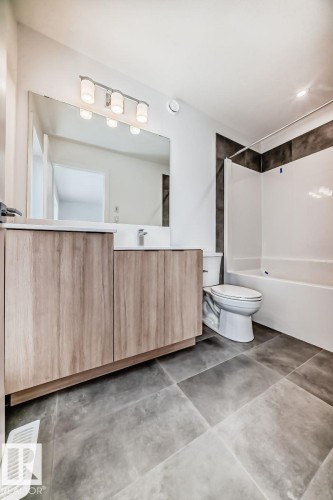 Modern bathroom featuring a wood-finish vanity with a white countertop and rectangular sink - #66 5 Rondeau Dr, St. Albert, AB - Indoor Photo Showing Bathroom