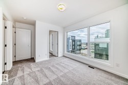 Spacious room featuring a large picture window, patterned carpeting, white walls, and contemporary doors - 