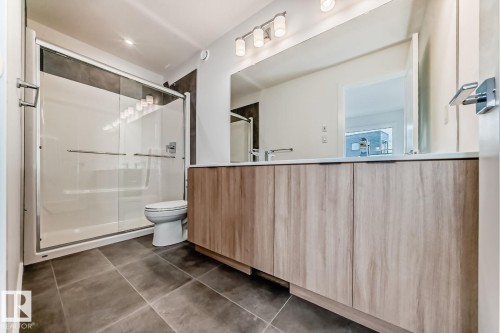 Bathroom featuring a wood-finish double vanity with white countertop, chrome fixtures, and a large mirror - #66 5 Rondeau Dr, St. Albert, AB - Indoor Photo Showing Bathroom