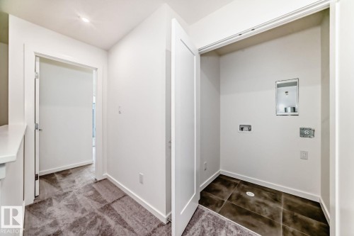 Dedicated laundry area with tile flooring and utility hookups, featuring a modern flat-panel door - #66 5 Rondeau Dr, St. Albert, AB - Indoor Photo Showing Other Room