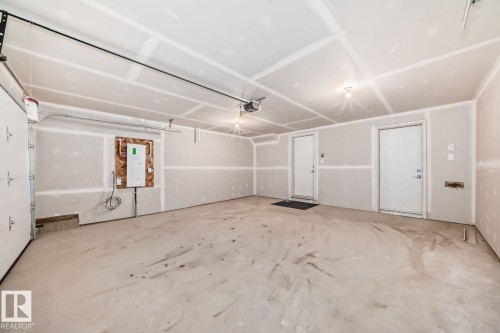 Spacious garage featuring a concrete floor, two interior access doors, and a built-in garage door opener - #66 5 Rondeau Dr, St. Albert, AB - Indoor Photo Showing Garage