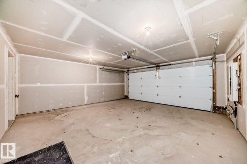 Spacious two-car garage featuring a sectional garage door, concrete flooring, and unfinished drywall walls and ceiling - #66 5 Rondeau Dr, St. Albert, AB - Indoor Photo Showing Garage