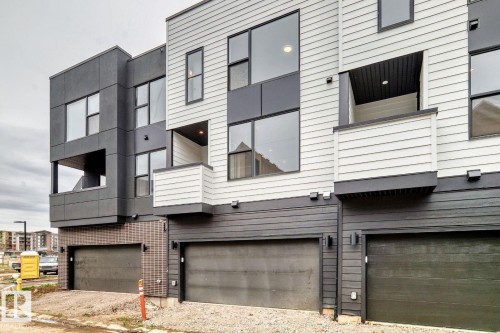Modern multi-level exterior featuring light gray horizontal siding, dark gray panels, large windows, and a private balcony - #66 5 Rondeau Dr, St. Albert, AB - Outdoor With Exterior