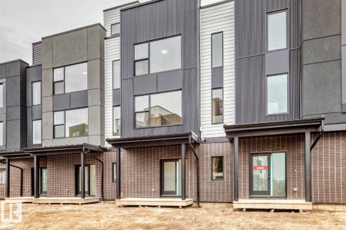 Modern townhome exteriors featuring multi-textured facades, large windows, covered patios, sliding glass doors, and durable brick-finish lower levels - #66 5 Rondeau Dr, St. Albert, AB - Outdoor